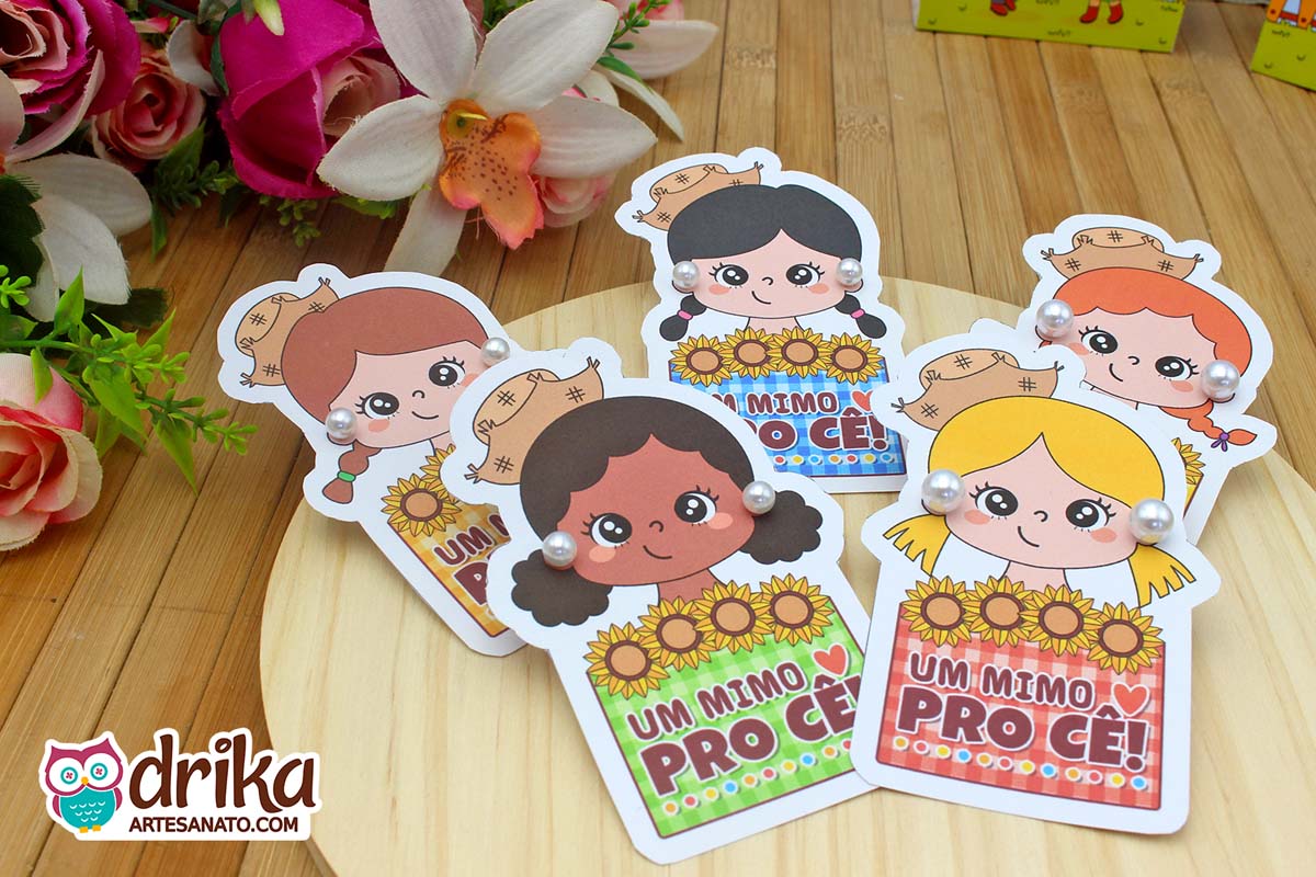 Grupo de cartões pérola menina caipira com variados tons de cabelo sobre madeira clara, brincos de pérola.
