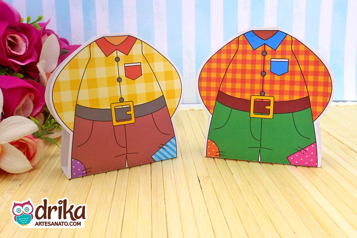 Dois porta bombons camisa caipira com estampas xadrez amarela e laranja lado a lado em cenário junino.