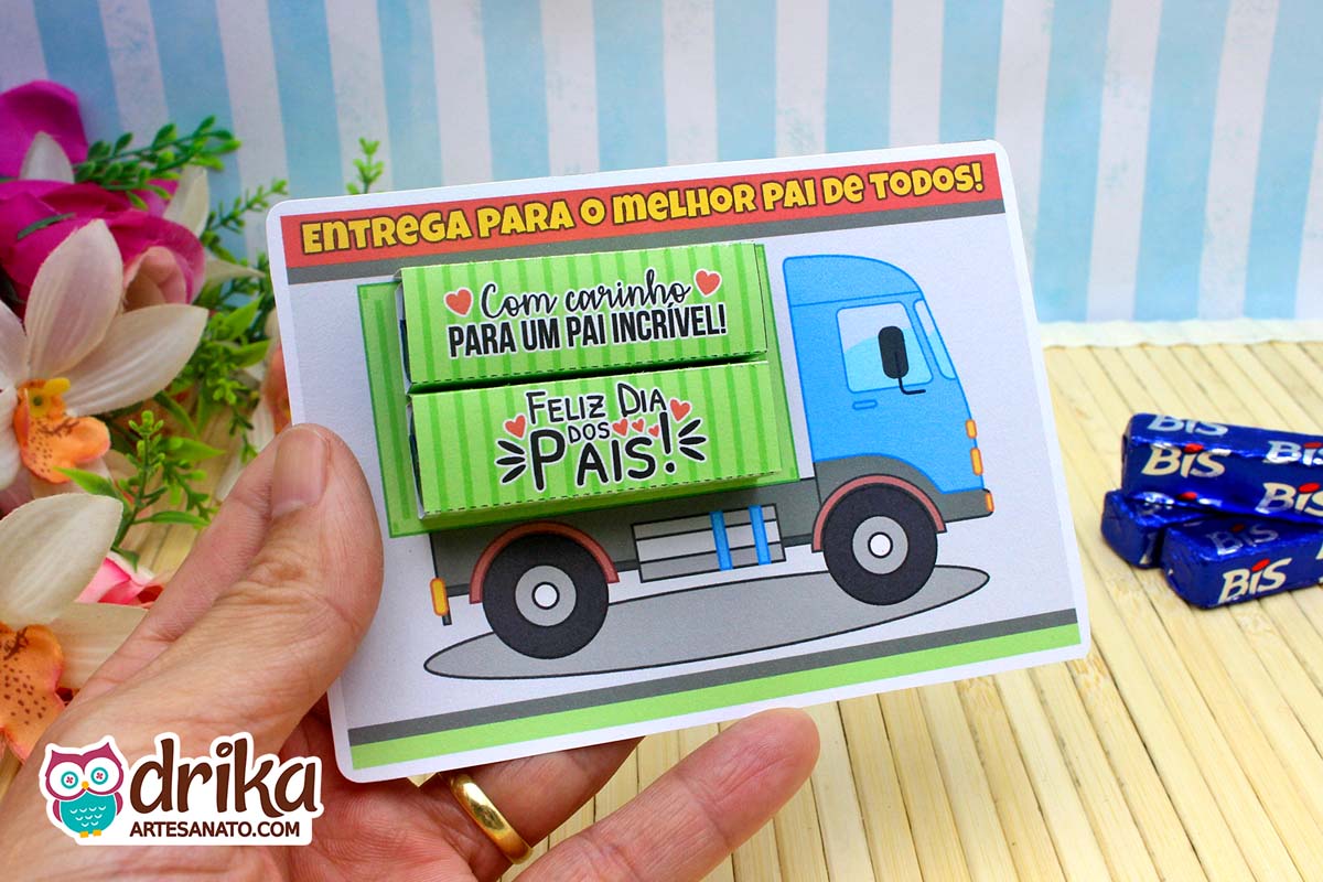 Mão segurando cartão de caminhão azul com chocolates Bis e embalagens de Bis ao lado